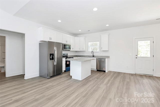kitchen featuring a center island, appliances with stainless steel finishes, light wood finished floors, and white cabinets