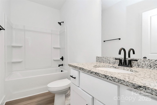 bathroom featuring washtub / shower combination, vanity, toilet, and wood finished floors