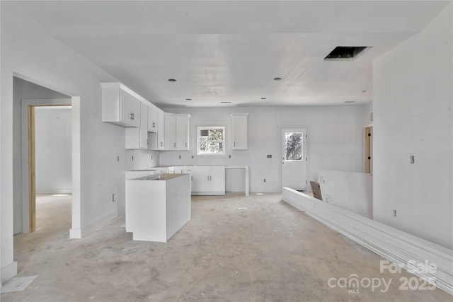 kitchen featuring unfinished concrete floors, white cabinetry, and a center island