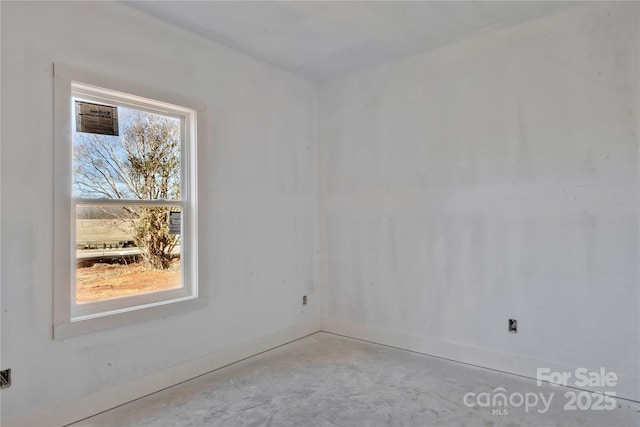 spare room featuring unfinished concrete floors and baseboards