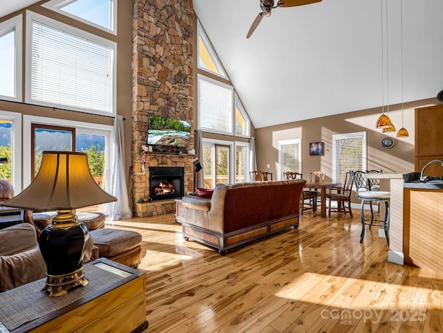 living room featuring a stone fireplace, high vaulted ceiling, and a healthy amount of sunlight