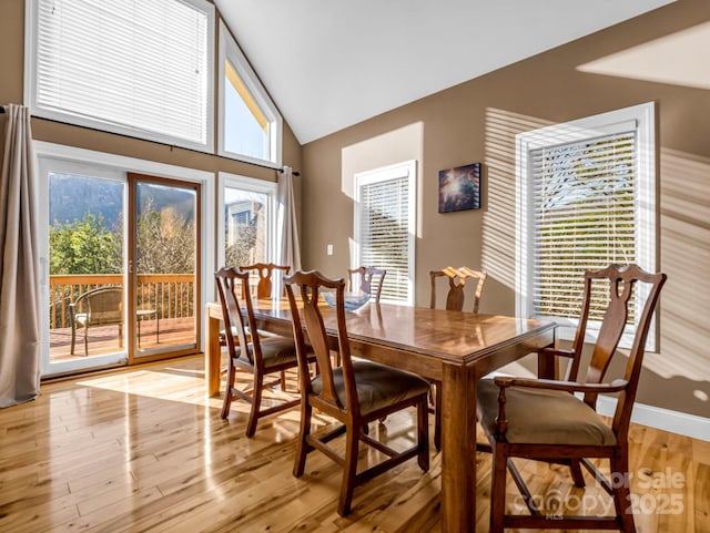 dining room with light wood-type flooring and high vaulted ceiling