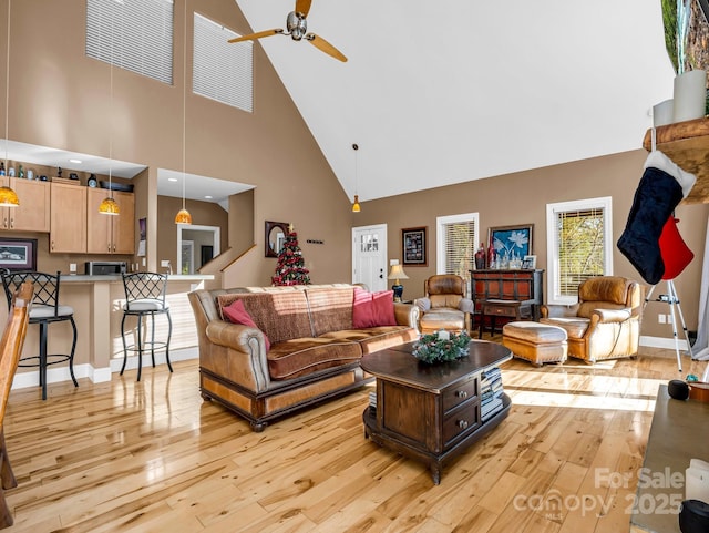 living room with ceiling fan, light hardwood / wood-style flooring, and a towering ceiling