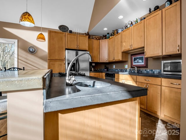 kitchen featuring a kitchen bar, appliances with stainless steel finishes, a center island with sink, dark tile patterned flooring, and decorative light fixtures