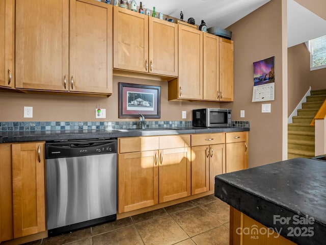 kitchen with sink, stainless steel appliances, and dark tile patterned flooring