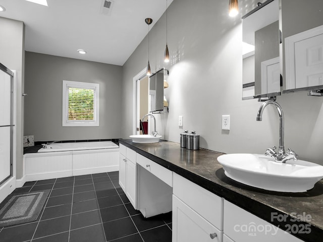 bathroom with a washtub, vanity, and tile patterned floors