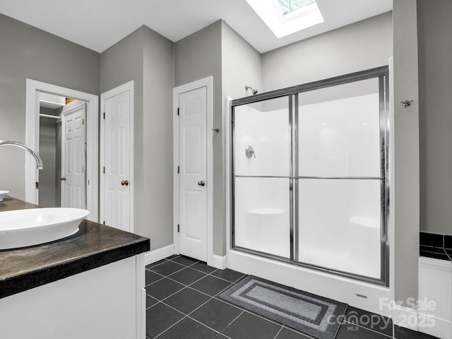 bathroom featuring vanity, a skylight, tile patterned floors, and walk in shower