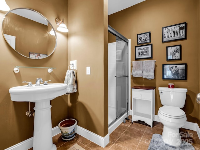 bathroom with tile patterned floors, toilet, and a shower with door