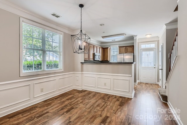 kitchen featuring an inviting chandelier, ornamental molding, appliances with stainless steel finishes, dark hardwood / wood-style flooring, and kitchen peninsula