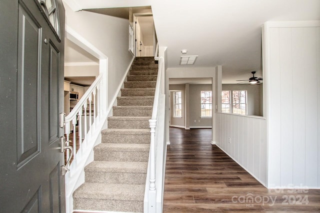 stairway with ceiling fan and wood-type flooring