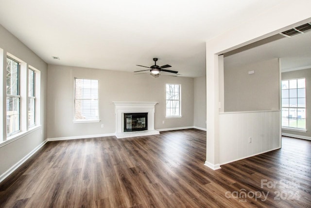 unfurnished living room featuring ceiling fan, plenty of natural light, and dark hardwood / wood-style floors