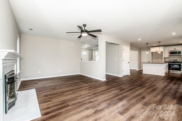 unfurnished living room featuring ceiling fan and dark hardwood / wood-style flooring