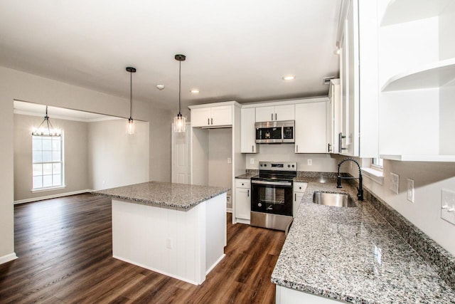 kitchen featuring appliances with stainless steel finishes, dark wood-type flooring, sink, white cabinets, and a kitchen island