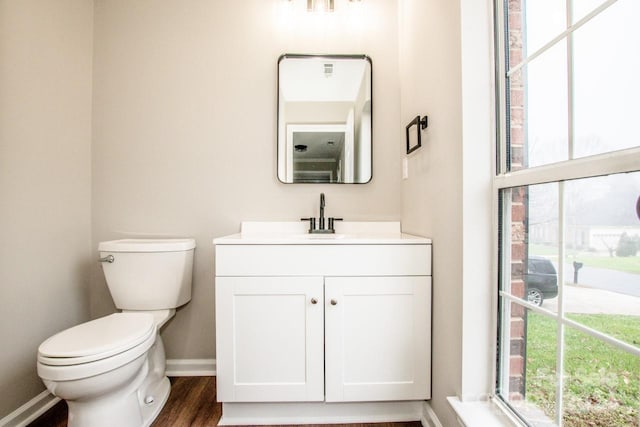 bathroom with toilet, plenty of natural light, vanity, and hardwood / wood-style flooring