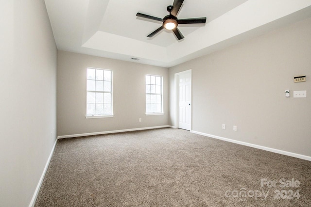 carpeted spare room featuring a raised ceiling and ceiling fan