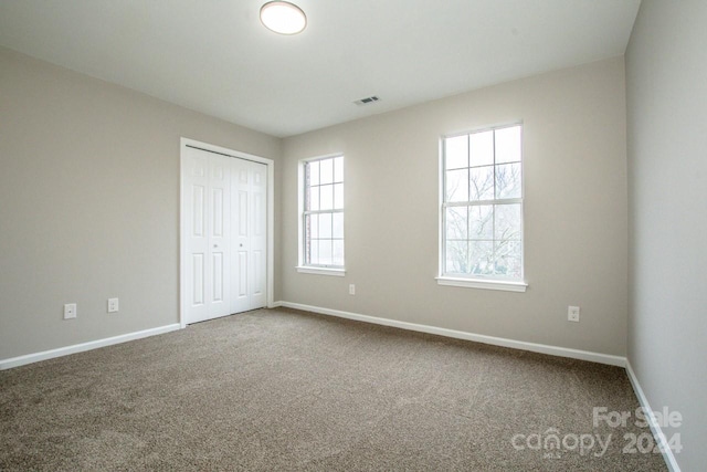 unfurnished bedroom with multiple windows, a closet, and carpet floors