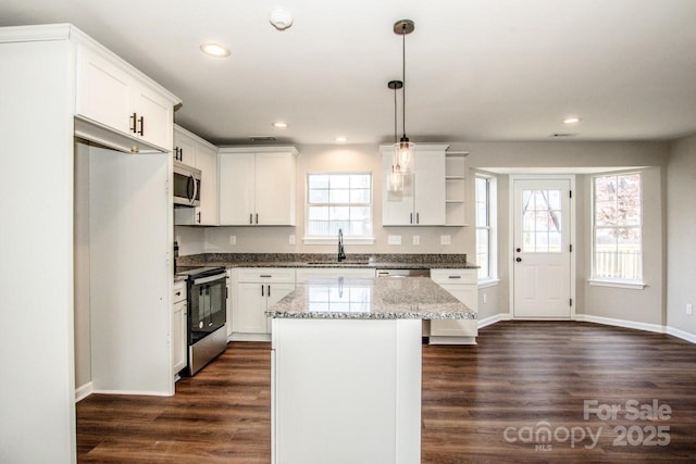 kitchen with stainless steel appliances, white cabinetry, a kitchen island, and sink