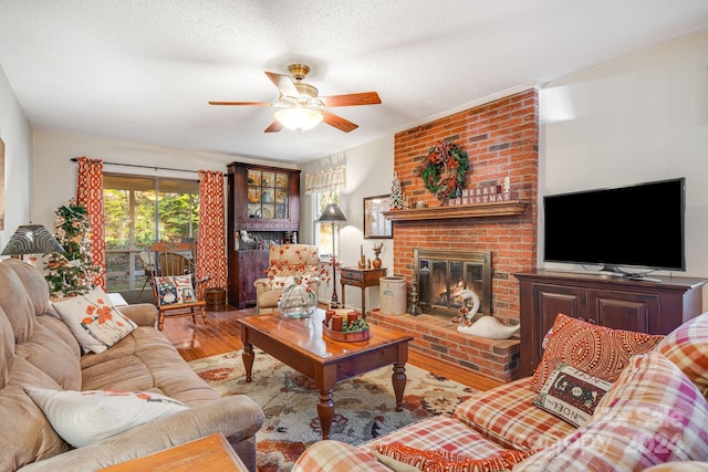 living room with ceiling fan, a fireplace, light hardwood / wood-style floors, and a textured ceiling