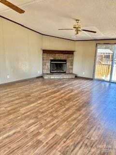 unfurnished living room featuring hardwood / wood-style floors, ceiling fan, and a stone fireplace