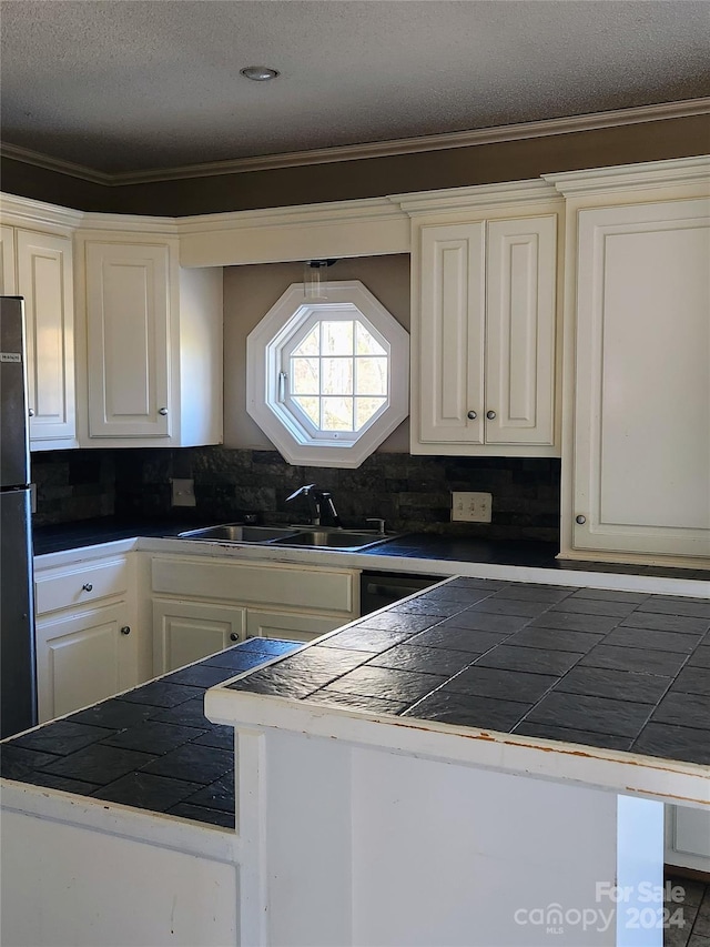 kitchen featuring tasteful backsplash, tile countertops, white cabinetry, and sink