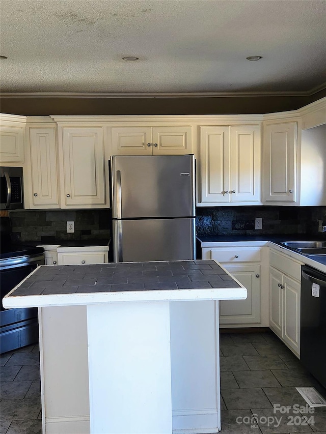 kitchen with sink, a kitchen island, decorative backsplash, white cabinets, and black appliances