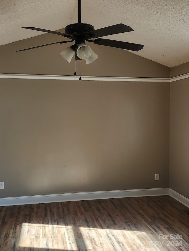 empty room with a textured ceiling, ceiling fan, dark hardwood / wood-style floors, and vaulted ceiling