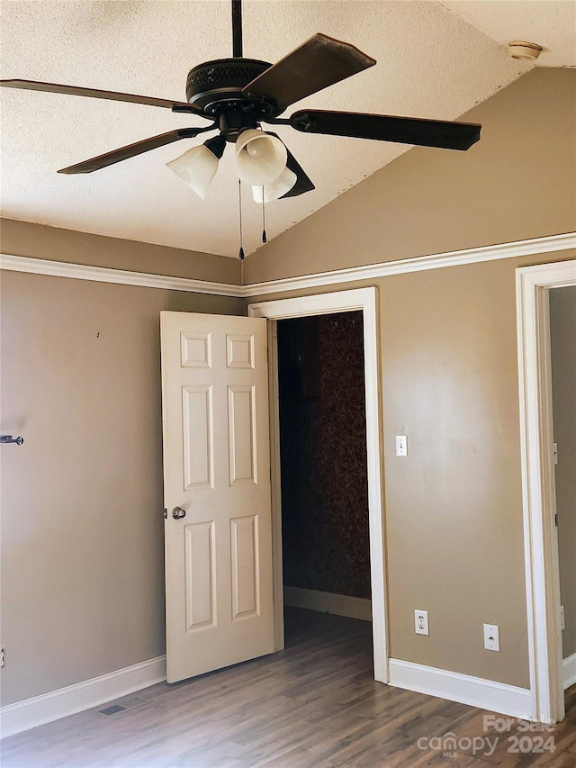 unfurnished bedroom with wood-type flooring, a textured ceiling, vaulted ceiling, and ceiling fan