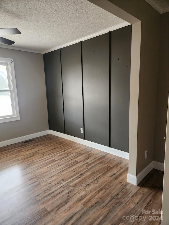 unfurnished room featuring hardwood / wood-style flooring, ceiling fan, and a textured ceiling