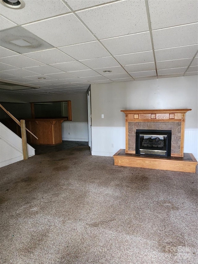 unfurnished living room featuring a fireplace, carpet floors, and a drop ceiling