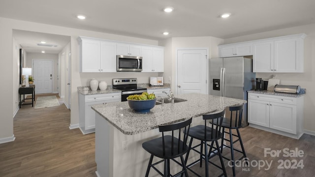 kitchen with dark hardwood / wood-style flooring, white cabinetry, an island with sink, and appliances with stainless steel finishes