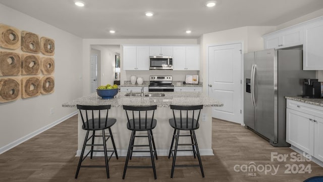 kitchen with stainless steel appliances, white cabinetry, dark hardwood / wood-style floors, and a kitchen island with sink