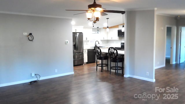 kitchen with electric stove, dishwasher, a breakfast bar area, white cabinets, and stainless steel fridge