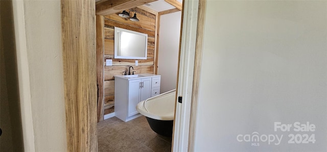 bathroom with a tub, wooden walls, and vanity