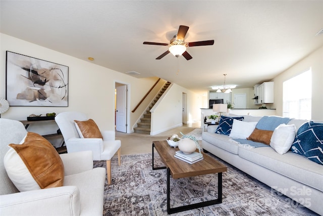 living room featuring light colored carpet and ceiling fan with notable chandelier