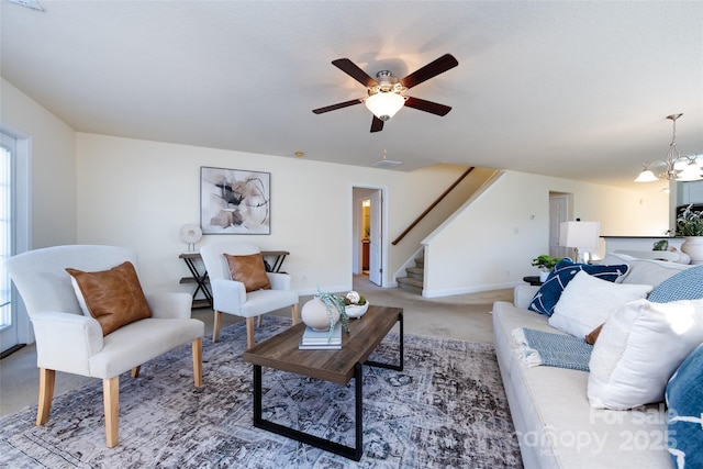 living room featuring ceiling fan with notable chandelier and carpet