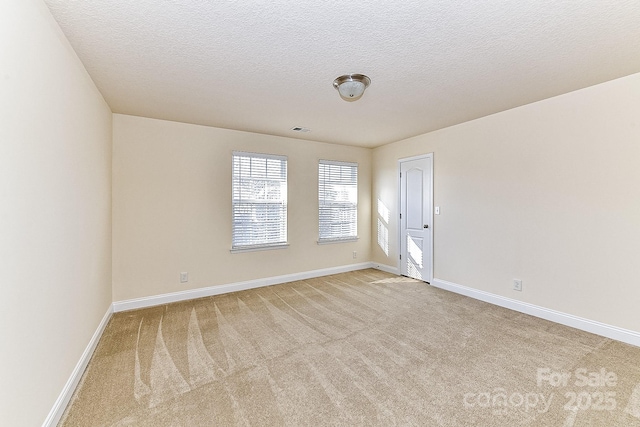 spare room with light carpet and a textured ceiling