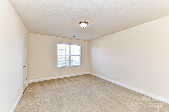 empty room with light colored carpet and a textured ceiling