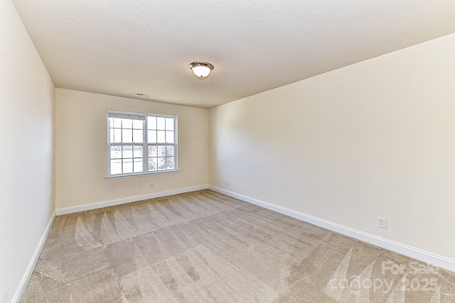 empty room with light carpet and a textured ceiling