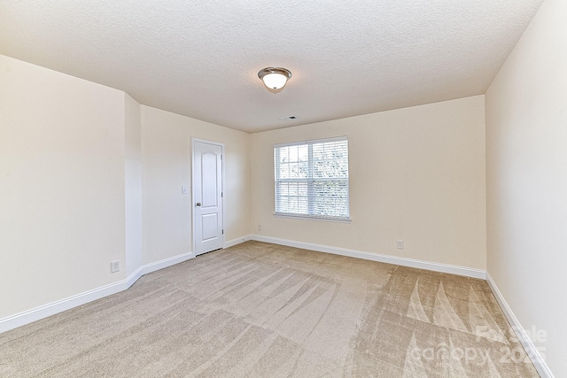 empty room with light carpet and a textured ceiling