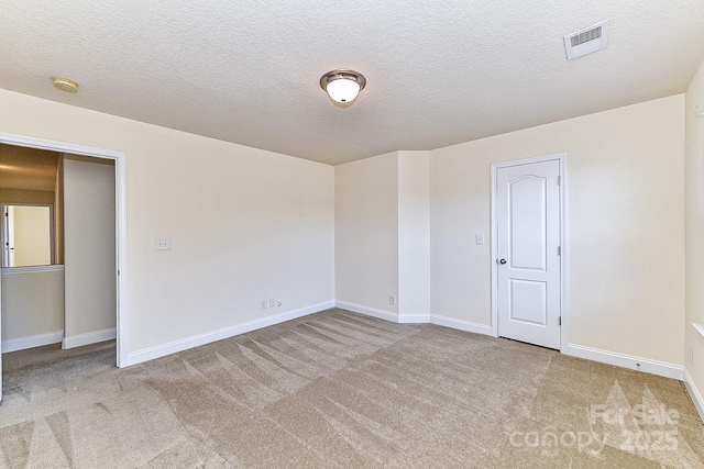 spare room featuring light carpet and a textured ceiling