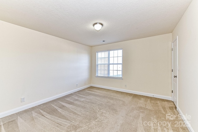 spare room with light carpet and a textured ceiling