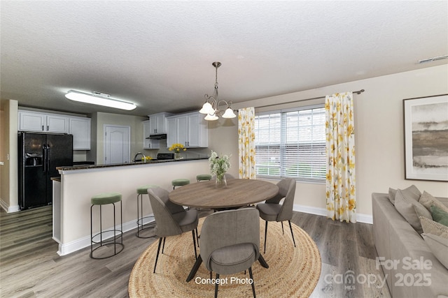dining space featuring visible vents, baseboards, wood finished floors, and a textured ceiling