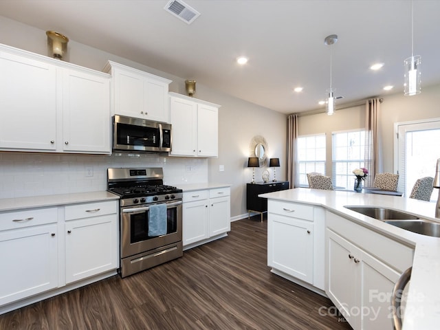 15533 Capps Rd, Charlotte, NC 28278 - kitchen featuring appliances with stainless steel finishes, decorative backsplash, dark wood-style flooring, light countertops, and hanging light fixtures