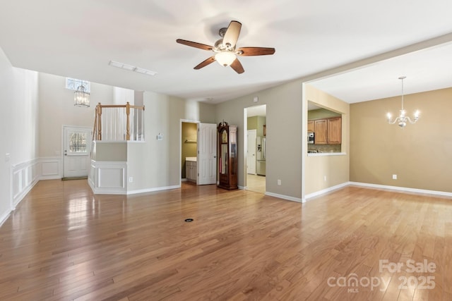 unfurnished living room featuring hardwood / wood-style flooring and ceiling fan with notable chandelier