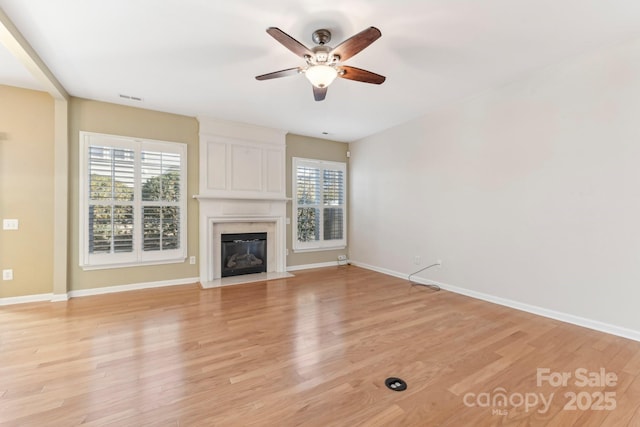 unfurnished living room with ceiling fan, light wood-type flooring, and a fireplace