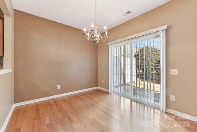 unfurnished room featuring a chandelier and light hardwood / wood-style floors