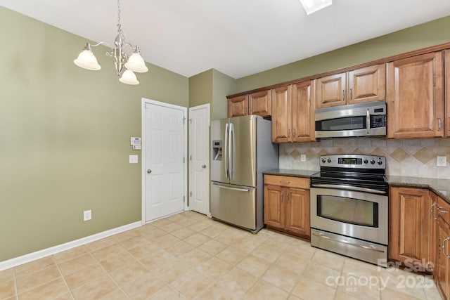 kitchen with stainless steel appliances, dark stone countertops, decorative backsplash, hanging light fixtures, and light tile patterned flooring