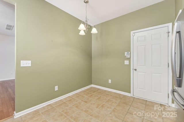 tiled spare room featuring an inviting chandelier and lofted ceiling