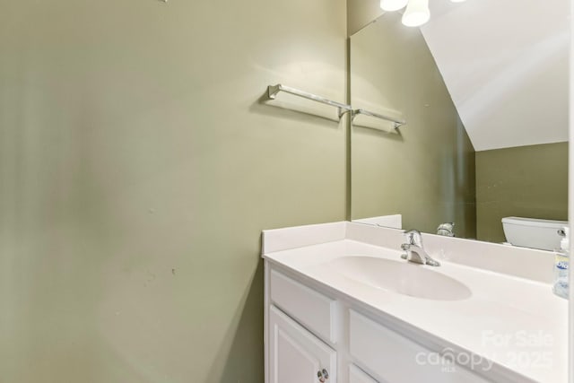 bathroom featuring toilet, lofted ceiling, and vanity