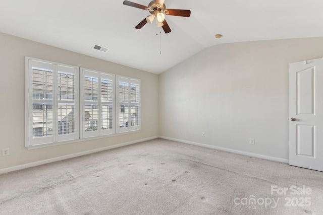 empty room with vaulted ceiling, ceiling fan, light colored carpet, and plenty of natural light